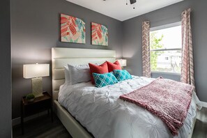 A bedroom with a large bed, a bedside table with a lamp, and two wall-mounted artworks. - Bright King Suite Near Dining, Shops & Parks (San Diego)