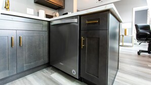 Eine moderne Küche mit dunklen Schränken, Edelstahlgeräten und Holzboden in heller Farbe.