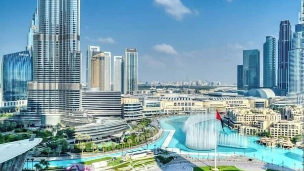 A modern cityscape with high-rise buildings, a waterfront promenade, and a large fountain. - Vogue| Opera Grand near Dubai Mall | Burj Khalifa (Dubai)