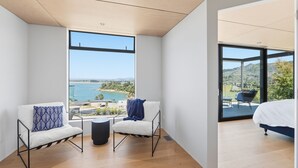 A modern bedroom with a large window overlooking a scenic landscape. - Luxury Bay Retreat in Kaiteriteri (Kaiteriteri)