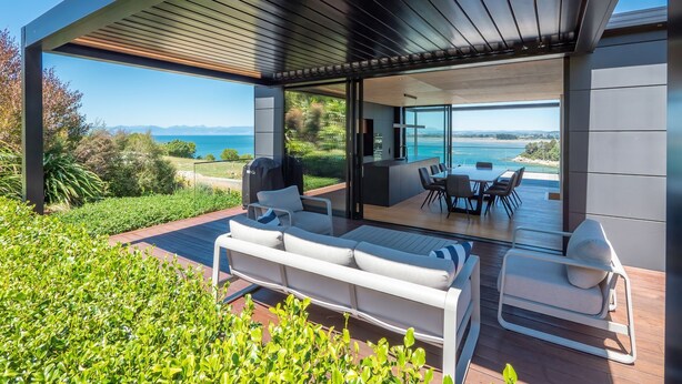 A modern outdoor living space with a patio, seating area, and a view of the ocean. - Luxury Bay Retreat in Kaiteriteri (Kaiteriteri)