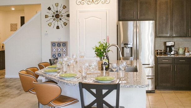 A modern kitchen with dark wood cabinets, a stainless steel refrigerator, and a granite countertop. - Spacious 5BR Retreat Sleeps 13 Premium Bedding Near NRG & Events (Houston)