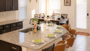 A kitchen with granite countertops, dark cabinets, and a dining area with a table set for six. - Spacious 5BR Retreat Sleeps 13 Premium Bedding Near NRG & Events (Houston)