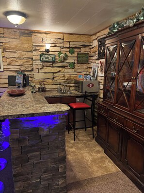 A bar area with a stone wall, a jukebox, a red bar stool, and a wooden cabinet. - Cozy 1-bedroom 1st floor in beautiful Pittsburgh with AC (Pittsburgh)
