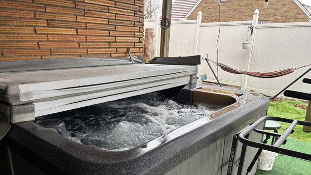 A hot tub with a cover, surrounded by a wooden fence and a hammock. - Cozy 1-bedroom 1st floor in beautiful Pittsburgh with AC (Pittsburgh)