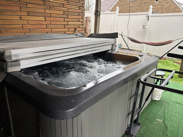 A hot tub with a cover, surrounded by a wooden fence and a hammock. - Cozy 1-bedroom 1st floor in beautiful Pittsburgh with AC (Pittsburgh)