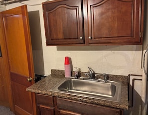 A kitchen with wooden cabinets, a granite countertop, a stainless steel sink, and a red and white striped cup. - Cozy 1-bedroom 1st floor in beautiful Pittsburgh with AC (Pittsburgh)