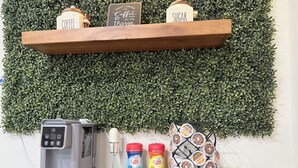 Une machine à café, deux récipients à café et une tasse contenant des dosettes de café, le tout posé sur une table en bois.