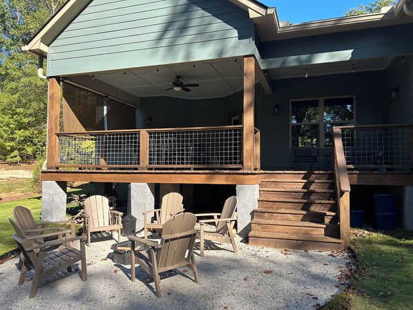 A covered deck with Adirondack chairs, a ceiling fan, and a staircase leading to a second level. - Driftwood Lodge on Lake Harding - On Quiet Cove with Kayaks and more (Valley)