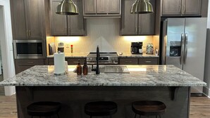 A modern kitchen with granite countertops, stainless steel appliances, and wooden cabinets.