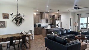 A modern kitchen with wooden cabinets, a central island, and pendant lighting.