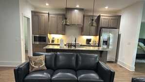 A modern kitchen with dark wooden cabinets, stainless steel appliances, and pendant lighting.