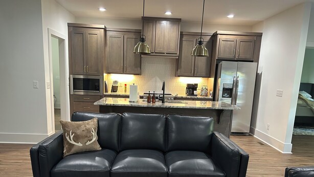 A modern kitchen with dark wooden cabinets, stainless steel appliances, and pendant lighting. - Driftwood Lodge on Lake Harding - On Quiet Cove with Kayaks and more (Valley)