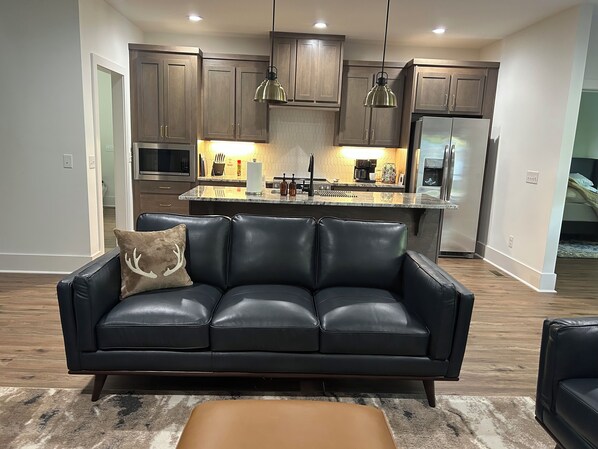 A modern kitchen with dark wooden cabinets, stainless steel appliances, and pendant lighting. - Driftwood Lodge on Lake Harding - On Quiet Cove with Kayaks and more (Valley)