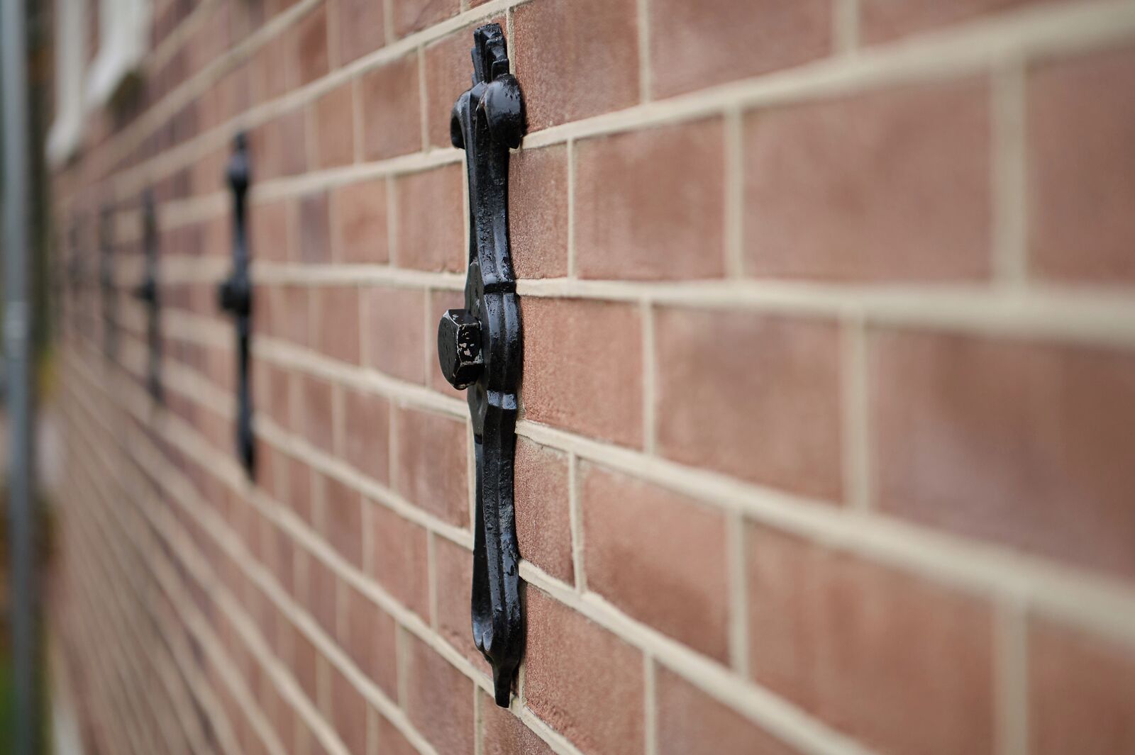 A close-up of a brick wall with metal fixtures, likely part of a building's exterior.