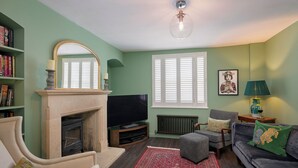 Ein Wohnzimmer mit Kamin, Fernseher, Sitzecke und Bücherregal.
