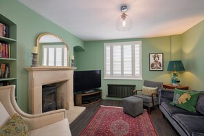 Ein Wohnzimmer mit Kamin, Fernseher, Sitzecke und Bücherregal.