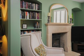 Une pièce avec une bibliothèque, une cheminée et un fauteuil.