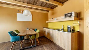 Een kleine keuken met een houten tafel en stoelen, een magnetron en een spoelbak.