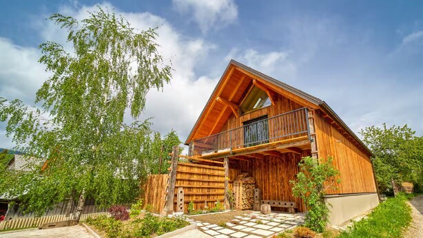 Een houten hut met een balkon, een pad van stenen en een tuin.