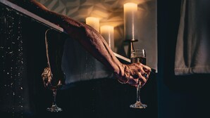A hand holding a wine glass over a wooden table with lit candles. - Suite Crazy'n love room, jacuzzi, cinema, parking, Camargue (Beaucaire)
