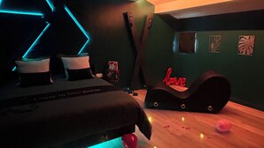 A modern bedroom with a bed, a desk, and a chair. There are decorative lights and heart-shaped objects on the floor. - Suite Crazy'n love room, jacuzzi, cinema, parking, Camargue (Beaucaire)