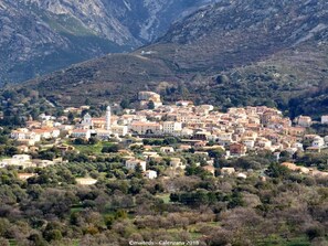 A town with a prominent church and dense buildings surrounded by mountains. - 3 rooms 6 pers • Terrace & garden - Calenzana near Calvi - Departure GR20 (Moncale)