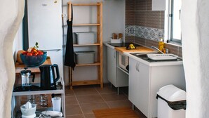 A compact kitchen with white cabinets, a wooden countertop, and a hanging light fixture.