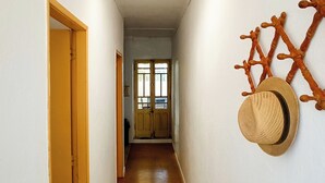 A hallway with wooden flooring, a rug, and a wall-mounted hat rack with hats.