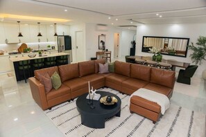 A modern living room with a sectional sofa, a coffee table, and a dining area with chairs.