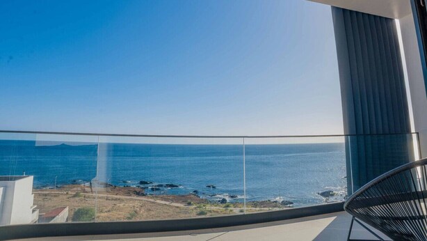 A balcony with a clear view of the ocean and a distant landmass.
