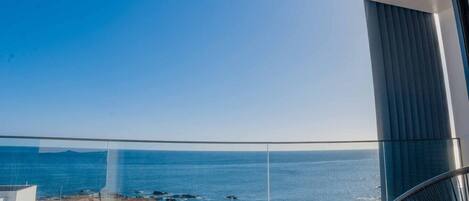 A balcony with a clear view of the ocean and a distant landmass.