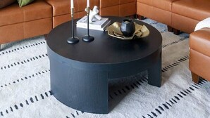 A modern living room with a brown leather sofa, a round coffee table, and pendant lighting.