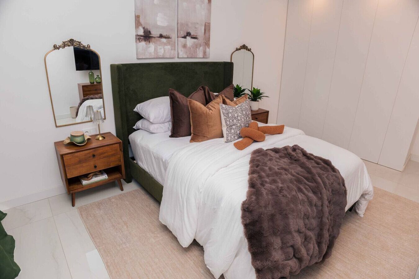 Une chambre bien rangée, avec un grand lit, une table de chevet, une commode et un miroir.