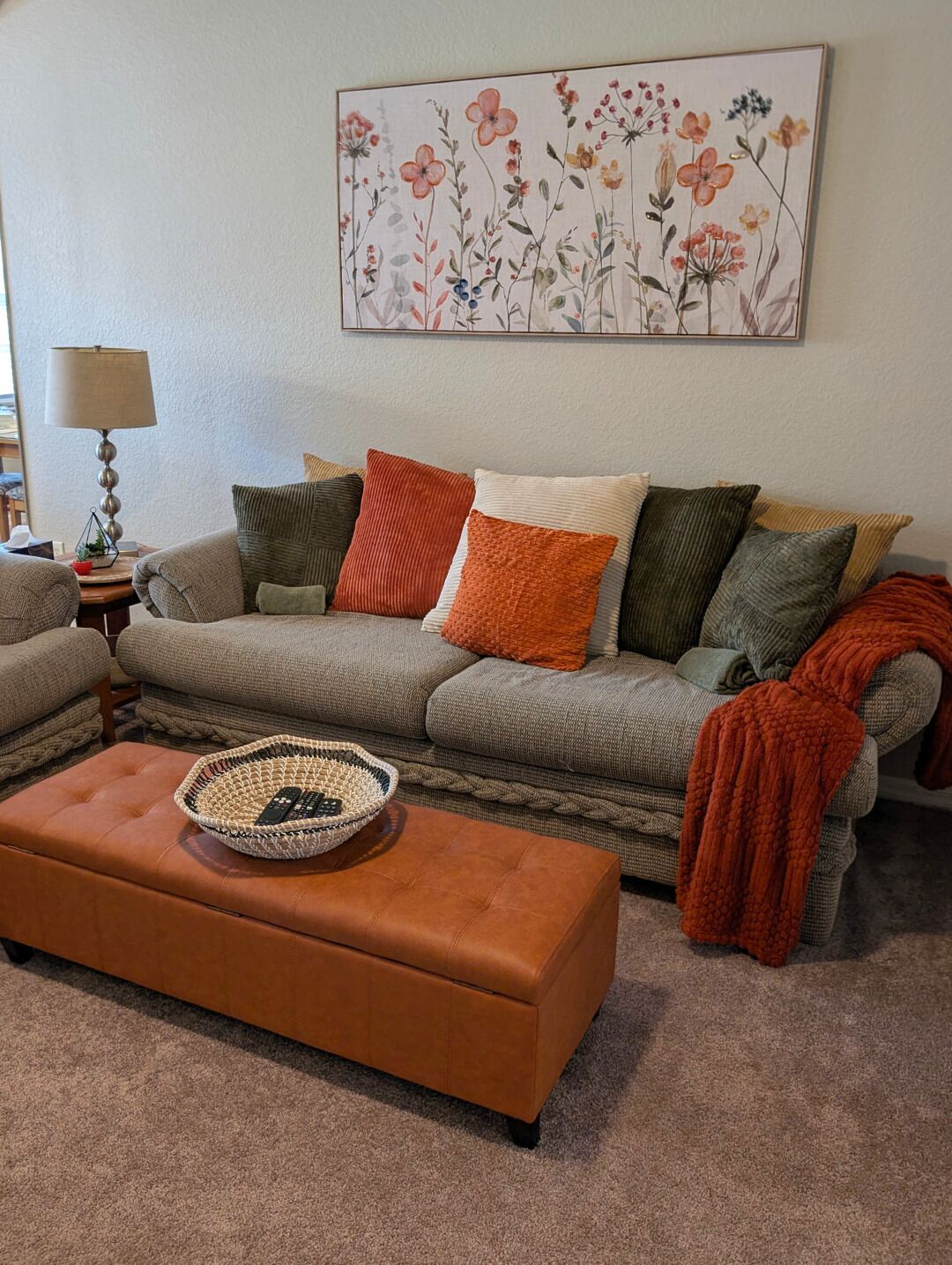 Ein Wohnzimmer mit einer Couch, Hocker und einer Wandlampe.