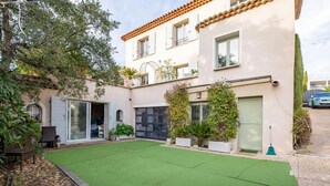 Un edificio de dos plantas con techo plano, un balcón y un césped artificial verde en el patio.