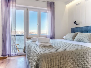 A bedroom with a bed, a view of the sea through large windows, and a balcony. - Sea&Mount by Interhome (Senj)