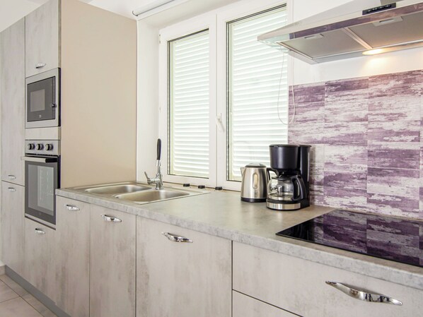 Una cocina moderna con electrodomésticos de acero inoxidable, un lavamanos doble y una cafetera.