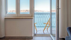 Ett rum med utsikt över ett bergigt landskap genom stora fönster och en skjutdörr i glas som leder ut till ett utomhusområde med en pool och en stol.