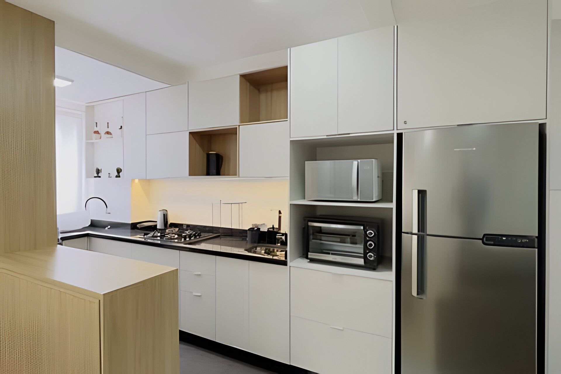 A modern kitchen with white cabinetry, a stainless steel refrigerator, a built-in oven, and a microwave.