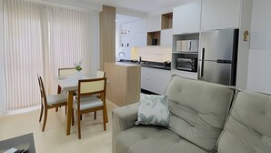A modern kitchen with white cabinets, a built-in oven, and a stainless steel refrigerator.