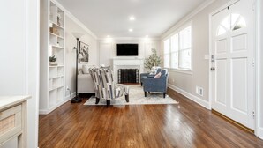 A living room with hardwood flooring, a fireplace, a television, and a bookshelf.
