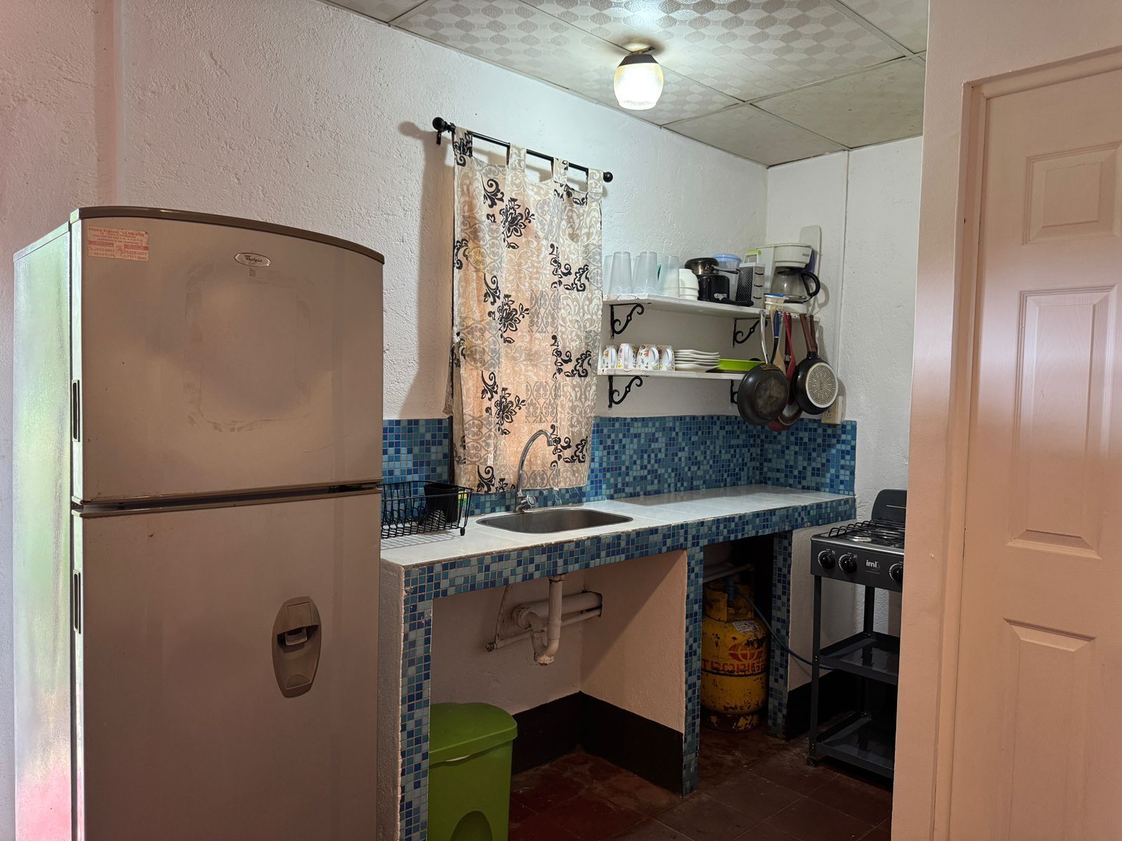 A compact kitchen with a refrigerator, sink, and a gas stove.