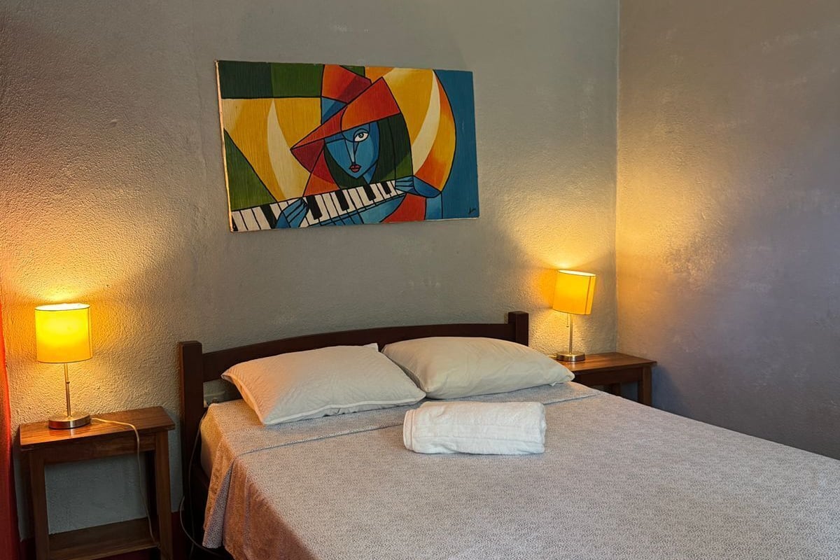 Une chambre d’hôtel avec un lit, deux lampes de chevet, un tableau au mur et une table de chevet en bois.