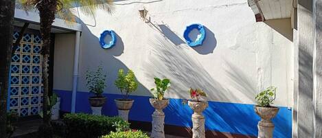A building with a white and blue exterior, potted plants, and a lattice door.