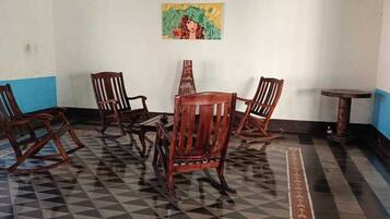 A room with a checkered floor, wooden chairs, a small table, and a painting on the wall.