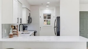 Una cocina moderna con armarios blancos, horno integrado y ventana.