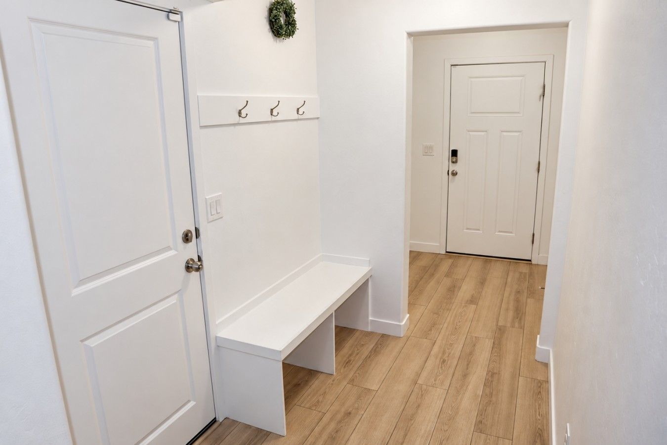 A hallway with a bench, a coat rack, and a door.