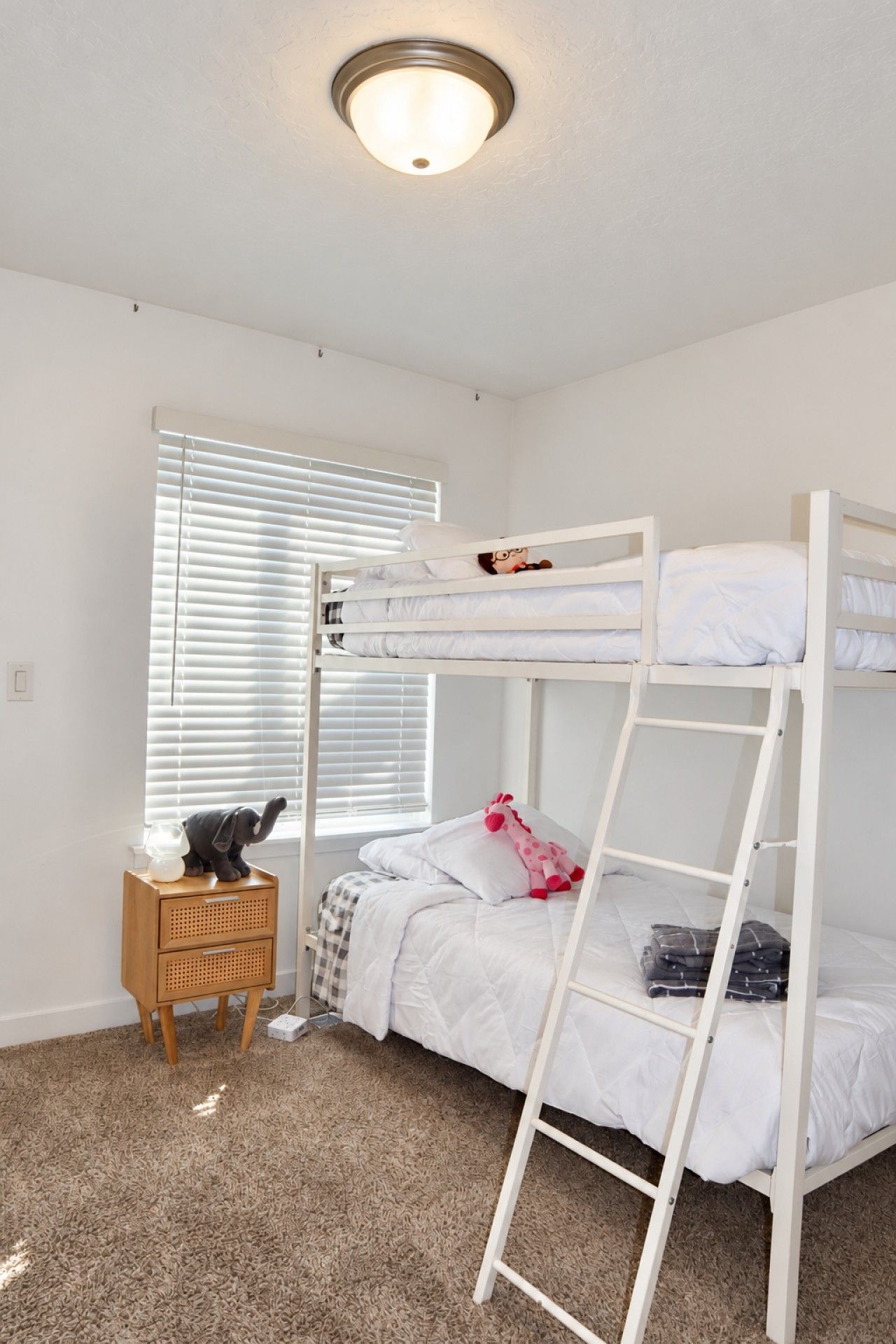 A bunk bed room with a wooden nightstand and a lamp.
