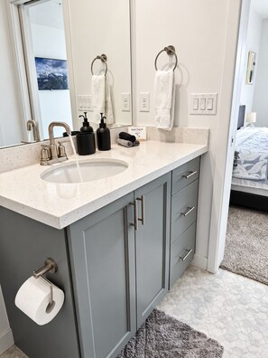 A bathroom with a sink, two towel rings, a toilet paper holder, and a mirror. - Elevated Urban Retreat | Views | Sleeps 7 + Pet (Riverton)